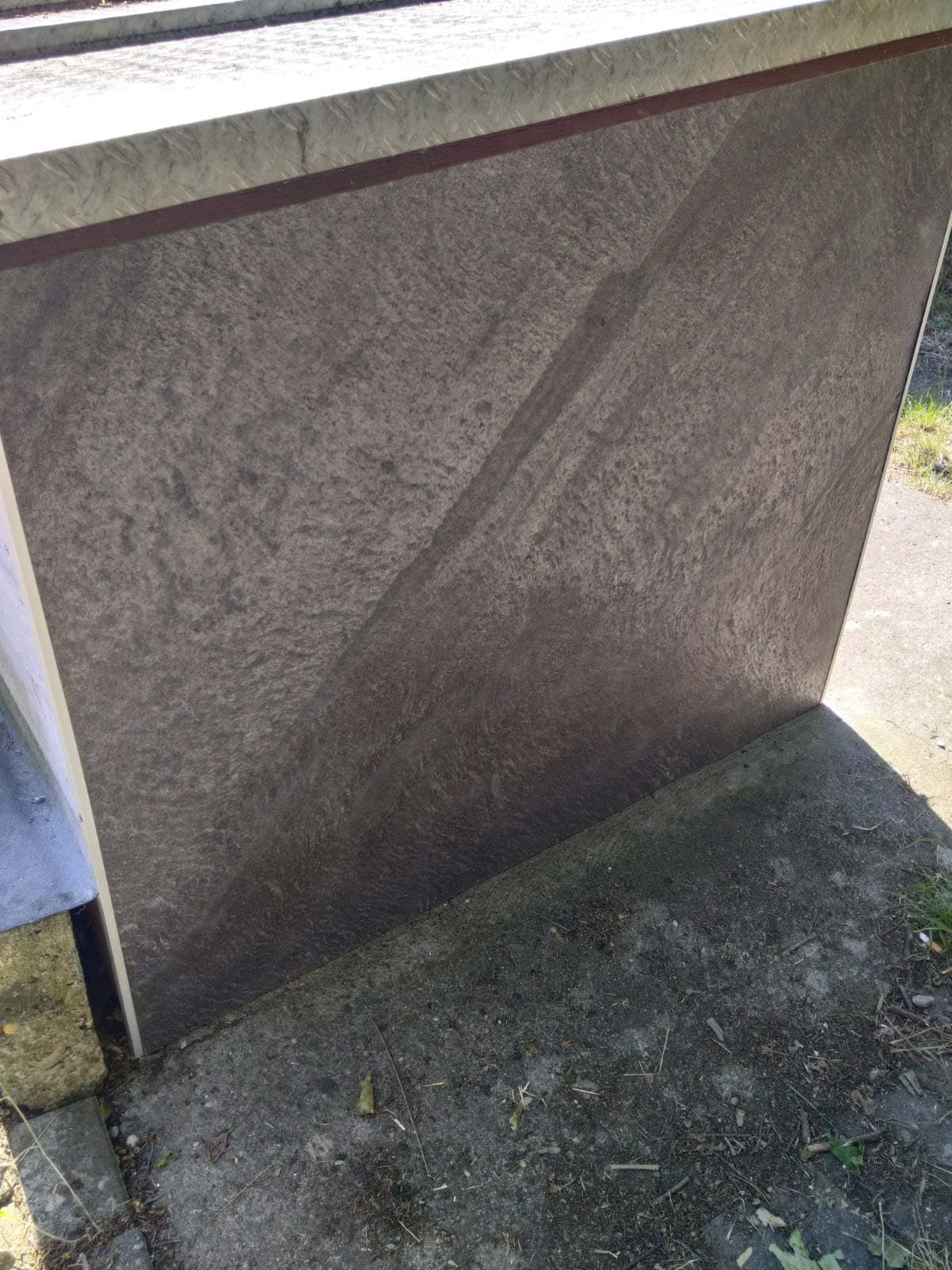 Außenmauer vollflächig mit dunklem Naturstein verkleidet