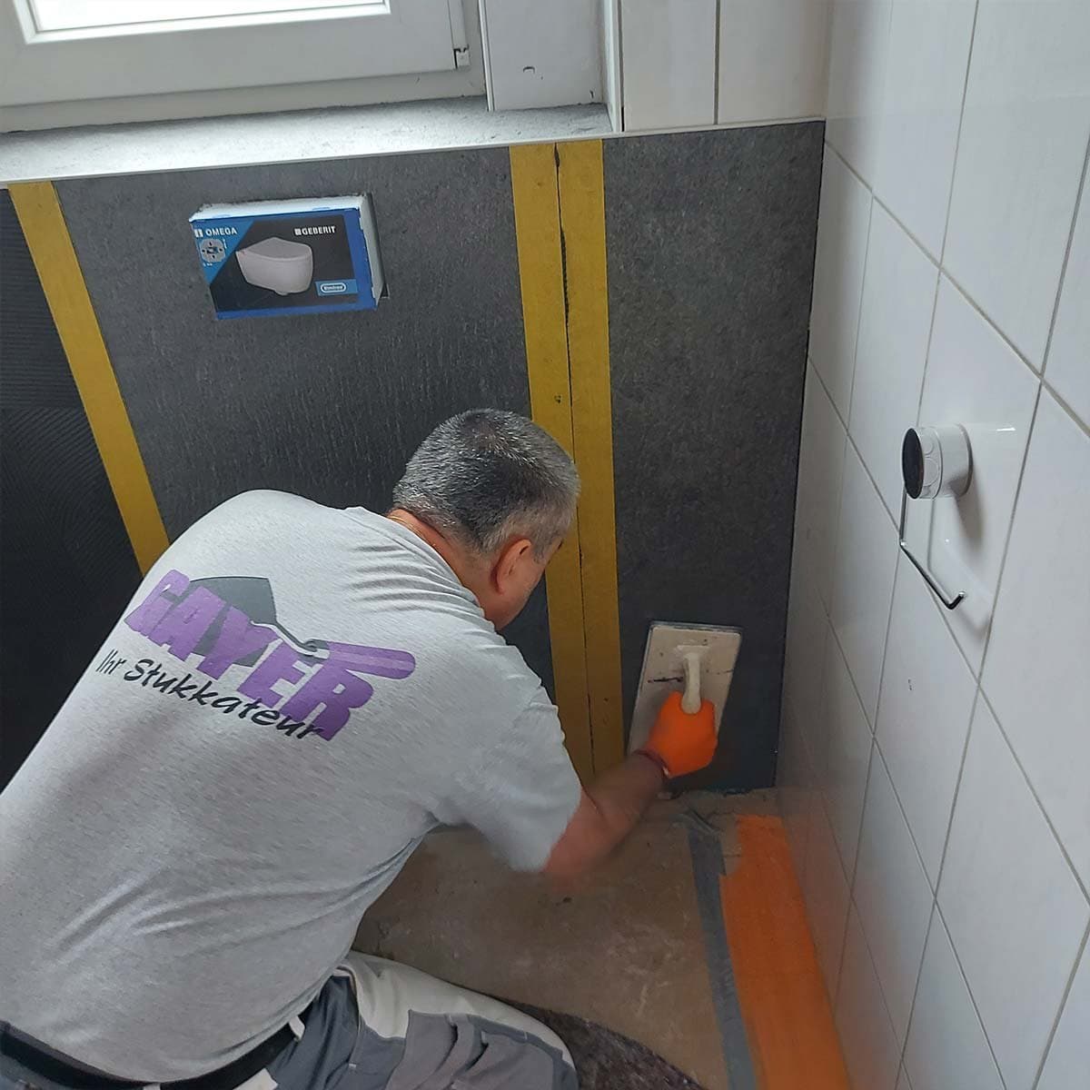 Handwerker von Gayer Stuck setzt eine Steinfurnierplatte im Bad an