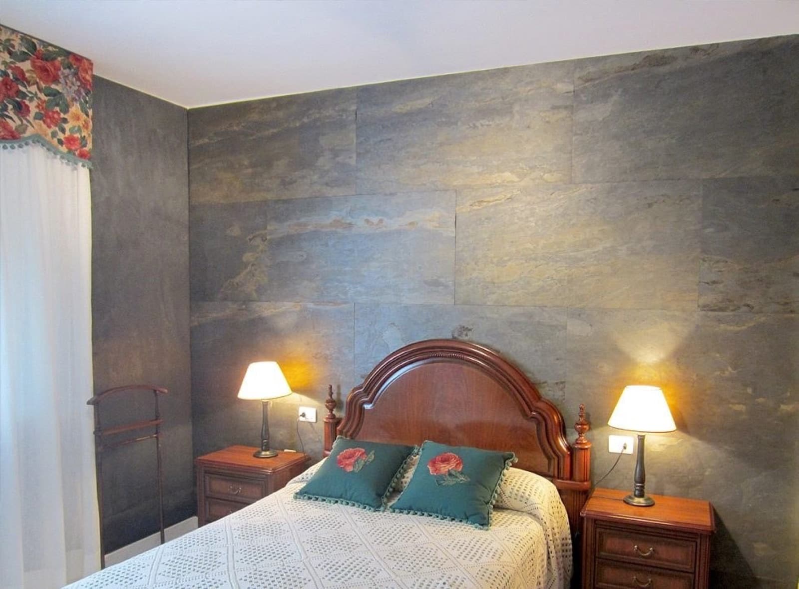 Schlafzimmer mit heller Sandsteinwand hinter dem Bett